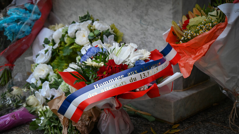 Ein Blumengesteck mit einer Schleife in den Farben der französischen Nationalflagge, auf dem steht: "Hommage an die Opfer der Anschläge vom 13. November 2015".