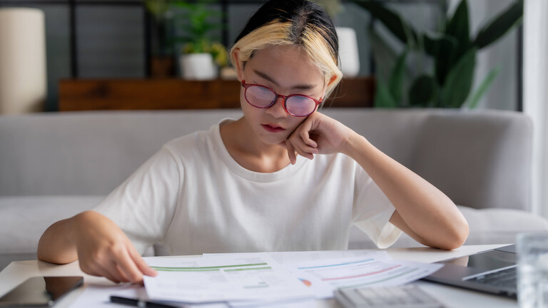 Frau blickt konzentriert auf Unterlagen, die vor ihr auf einem Tisch liegen