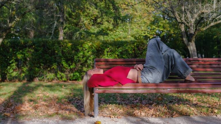 Eine Frau liegt auf einer Bank im Park