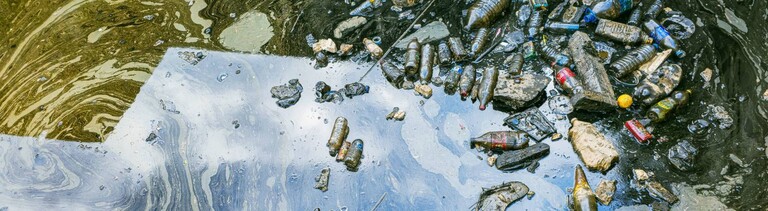 Starke Wasserverschmutzung in einem Stadthafen in Izmir, Konak, Türkei, sichtbar: Treibende Plastikflaschen, Müll und ein giftiger Ölteppich treiben auf der Wasseroberfläche.