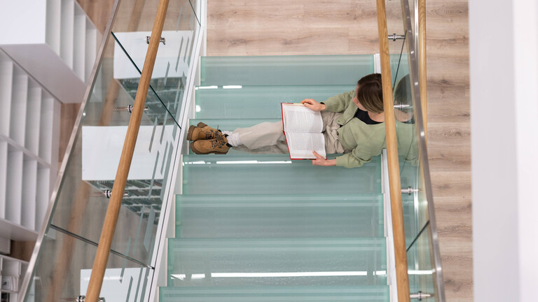 Fleißige Studentin bereitet sich auf Kursarbeit in Philosophie vor, indem sie Bücher liest, um Informationen zu finden.