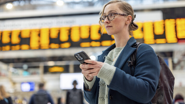 Eine Pendlerin blick von ihrem Smartphone auf.