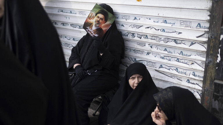 Eine verschleierte Iranerin lehnt sich während einer Jubeldemonstration für Mojtaba Khamenei Anfang März 2026 an die Jalousie eines Geschäfts.