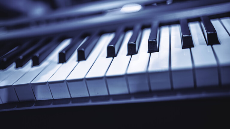 Die Tasten eines modernen E-Pianos, die die Details der schwarzen und weißen Elemente zeigen und dabei musikalische Kreativität sowie das Spiel in einem kühlen Blauton hervorheben.