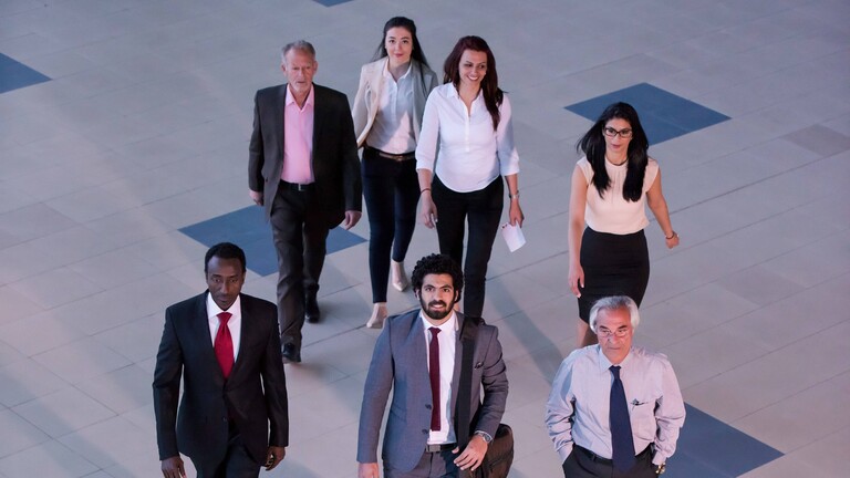 Ein Team aus Fachleuten unterschiedlicher Disziplinen, das selbstbewusst durch eine moderne Firmenlobby schreitet