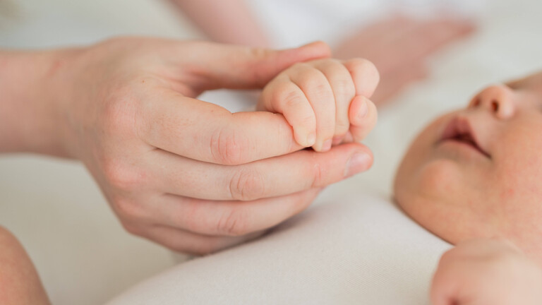 Eine Mutter hält die Hand ihres Babys