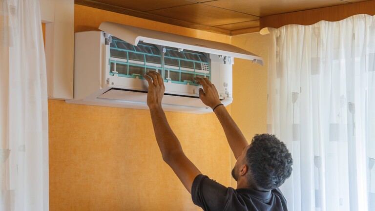 Ein Mann installiert eine Klimaanlage im Wohnzimmer