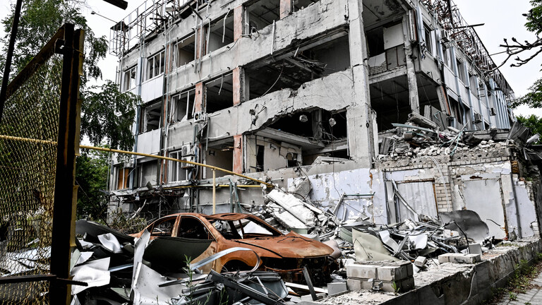 Durch russische Angriffe zerstörtes mehrstöckiges Wohnhaus und ausgebranntes rotes Autowrack (10.06.2026)