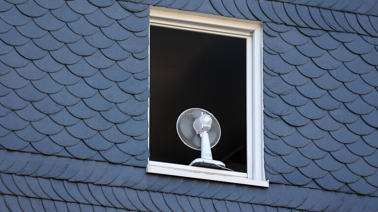 Nach einer sehr warmen Nacht ist ein Fenster in einem Haus am Morgen komplett geöffnet um die Wohnung zu lüften.