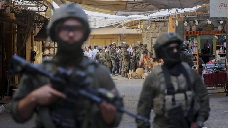 Bewaffnete israelische Soldaten bewachen und begleiten israelische Siedler bei ihrem Rundgang durch die Altstadt von Hebron.