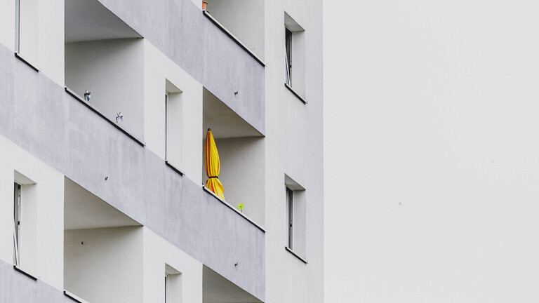 Zusammengefalteter Sonnenschirm auf Balkon