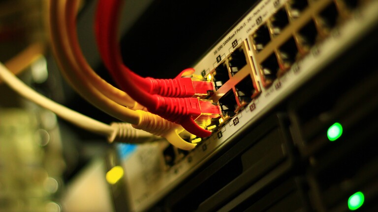 Nahaufnahme eines arbeitenden Ethernet-Switchs mit UTP-kabeln und geöffneten Ports.
