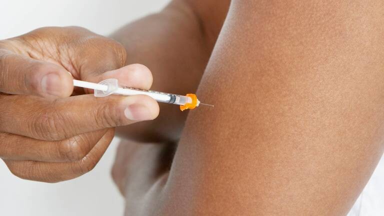 Person injiziert Insulin in Oberarm