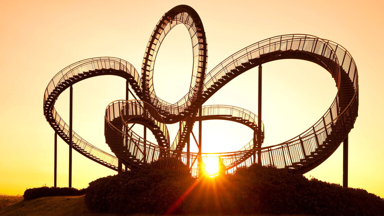 Die einer Achterbahn nachempfundene Großskulptur Tiger and Turtle vor einem Sonnenaufgang
