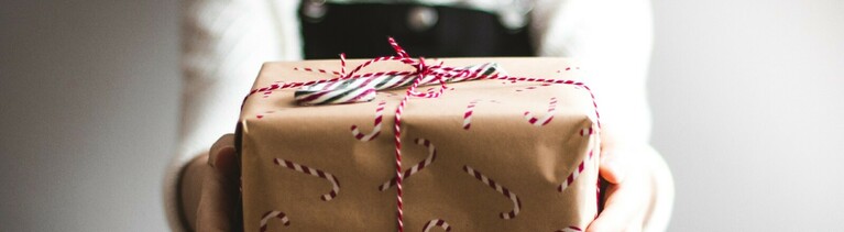 Eine Frau hält ein Geschenk in die Kamera.