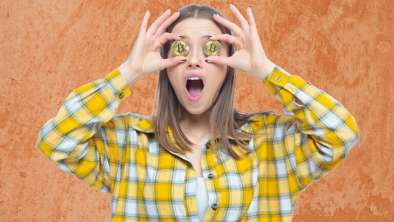 Eine Frau hält sich Bitcoin-Münzen vor die Augen