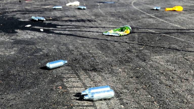Lachgas-Kartuschen und Luftballons liegen auf der Straße. Legal, billig und ungefährlich: Das ist das Image von Lachgas. In den Niederlanden nimmt der Konsum und Handel zu
