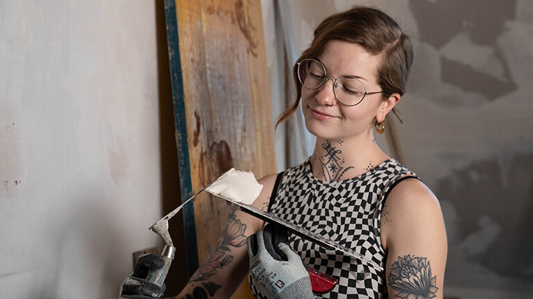Die Content Creatorin Lisa aka Die Hauswerkerin streicht Putz auf eine Glättkelle.
