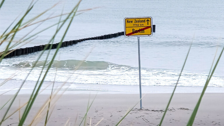 Ein Schild, dass den Entfernung zwischen Berlin und Neuseeland