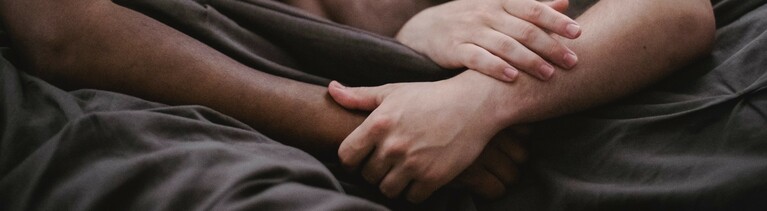 Zwei unbekleidete Männer liegen im Bett