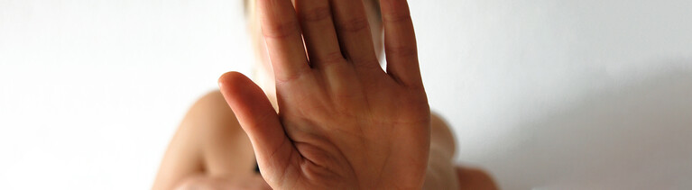 Frau hält eine Hand abwehrend vor sich.