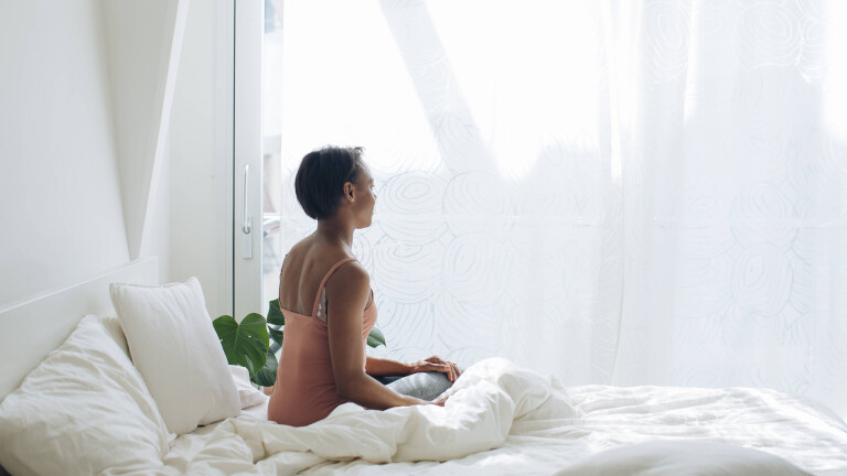 Frau sitzt alleine im Bett