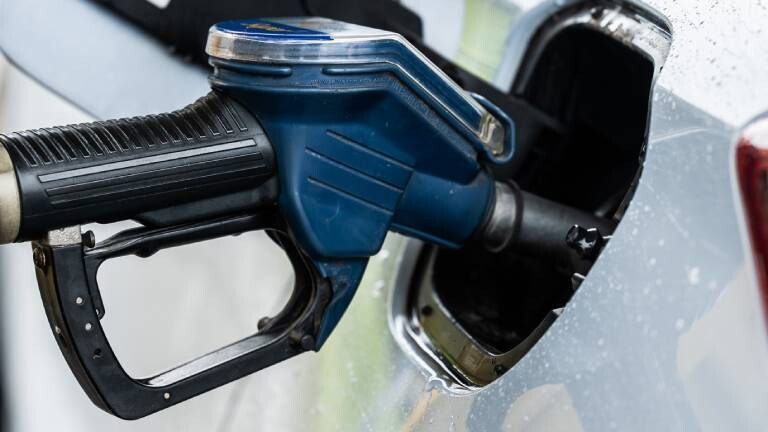 Ein Auto wird an einer Zapfsäule mithilfe eines Tankrüssels an einer Tankstelle betankt.