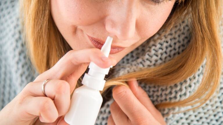 Eine Frau benutzt ein Nasenspray.