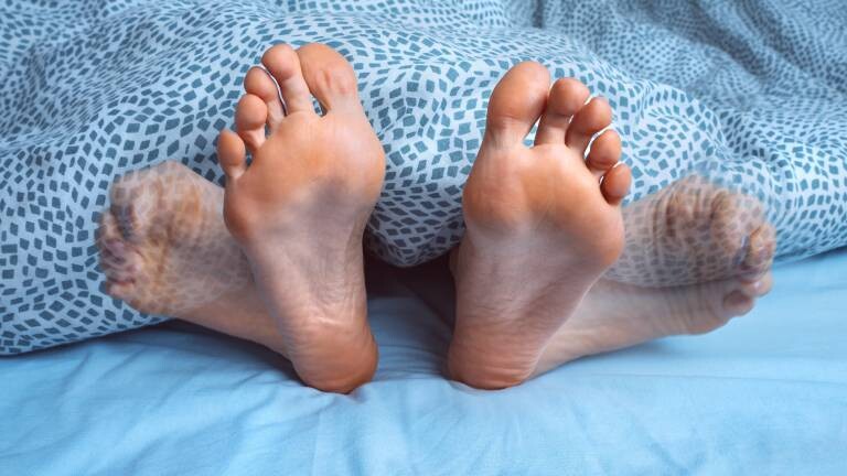 Frau leidet nachts unter Fuß-, Beinkrämpfen oder Muskelverspannungen. Fußschmerzen oder -krämpfe. Restless-Legs-Syndrom.