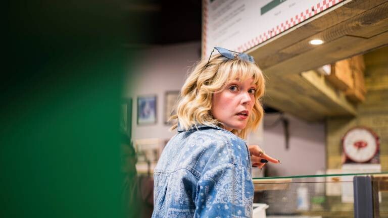 Eine Person schaut auf einer Party in einer Pizza-Bar besorgt, weil sie etwas verpasst hat.