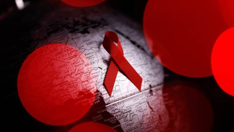 Symbolbild: Die Aidsschleife vor einem Globus.