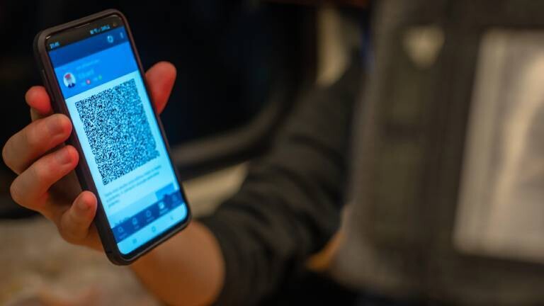Ein Zug-Passagier zeigt Kontrolleur sein digitales Ticket auf dem Smartphone.