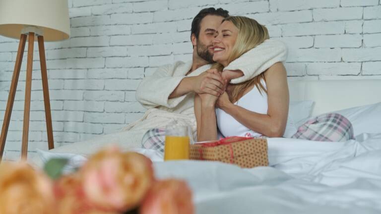 Ein verliebtes Pärchen frühstückt nach dem Aufwachen im Bett.