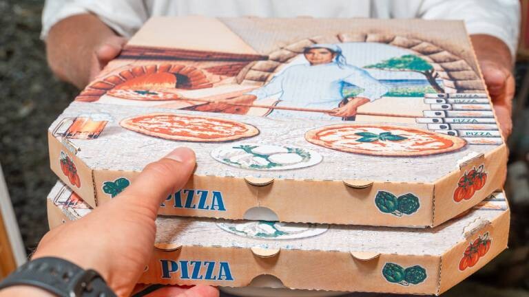 Ein Pizzalieferant übergibt zwei Pizzaschachteln