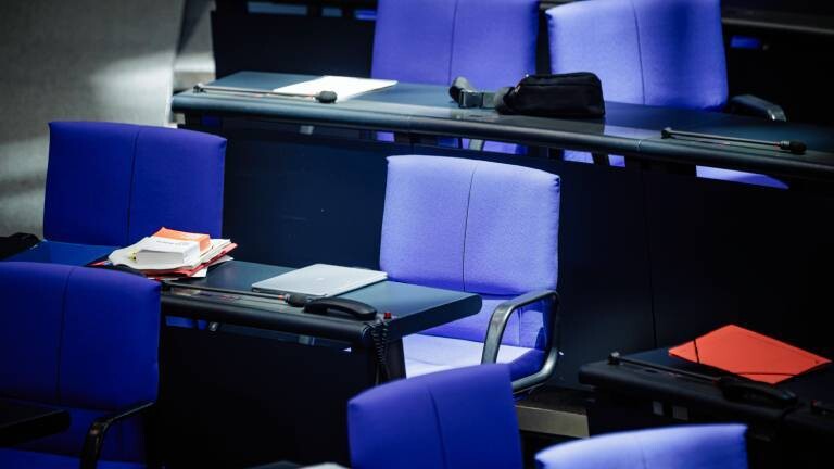 Leere Stühle einiger Politiker im Bundestag.