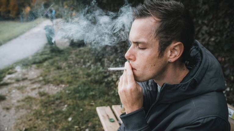 Junger Typ zieht an einer brennenden Zigarette