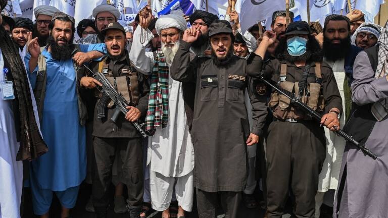 Anhänger der Taliban feiern in Kabul die Machtübernahme der Islamisten vor vier Jahren. Einige von ihnen skandieren Parolen und haben eine Waffe in den Händen.